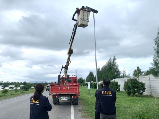 เจ้าหน้าที่ ป.ป.ช. ยืนสังเกตการณ์ขณะรถกระเช้ายกช่างขึ้นตรวจโคมไฟส่องสว่างริมถนน